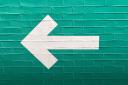 A white arrow on a blue brick wall