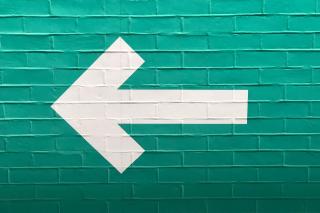 A white arrow on a blue brick wall