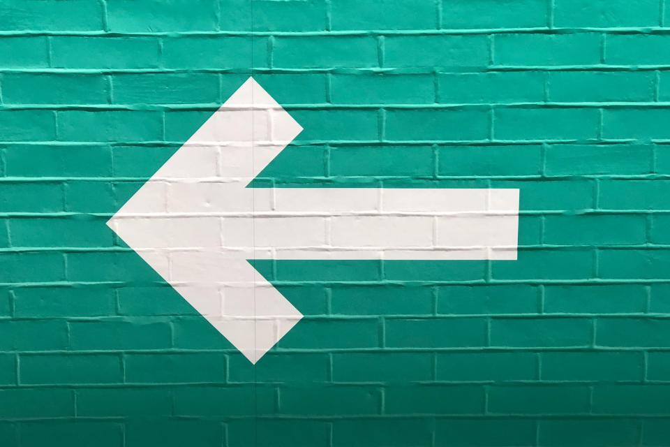 A white arrow on a blue brick wall